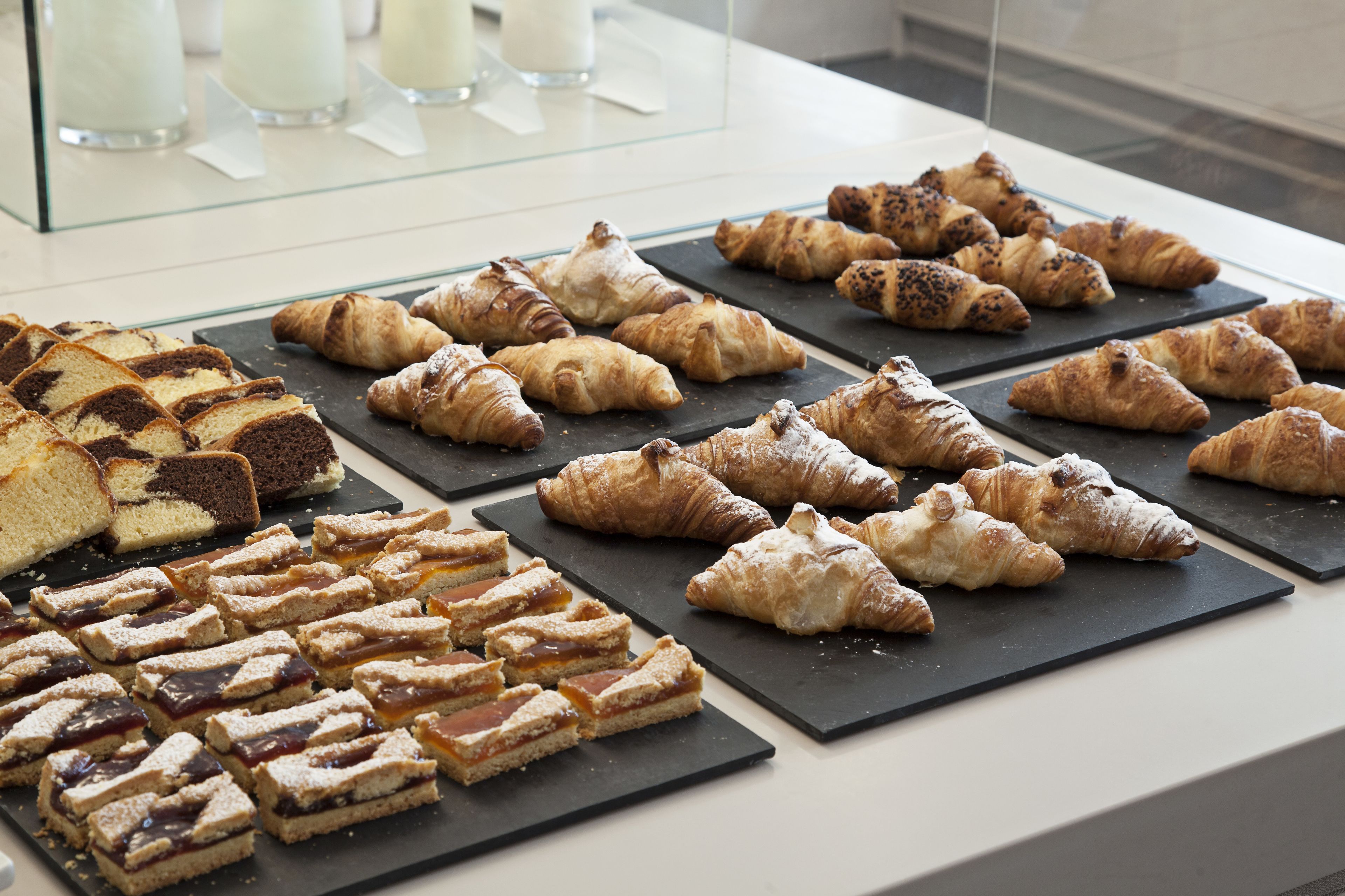 Une variété de pâtisseries et de desserts présentés sur des planches d’ardoise noire, dans un décor de boulangerie.