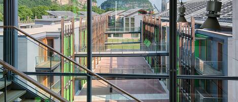 Un edificio moderno con varios pisos, amplias ventanas y vistas a un paisaje montañoso.