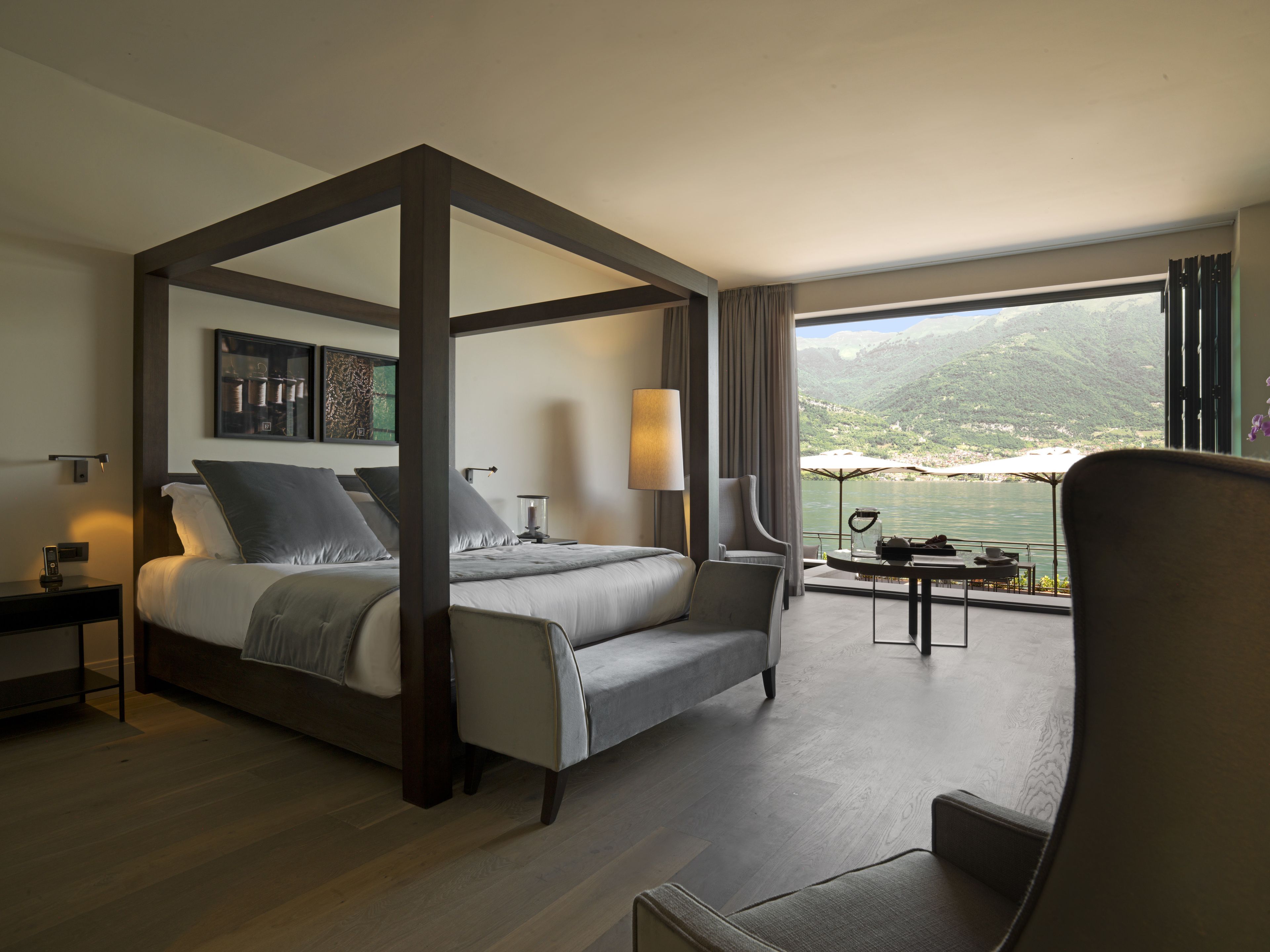 Una cama con dosel que ofrece vistas a un lago y montañas.