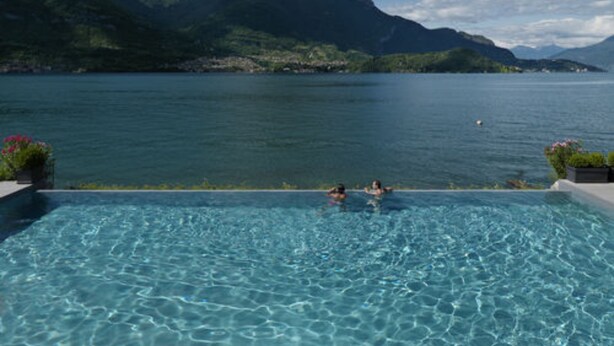 An infinity pool with a view of a lake and mountains.