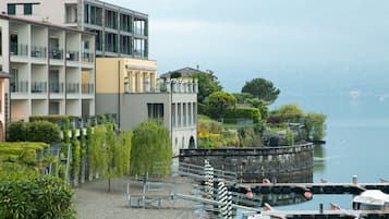 A multi-story hotel with balconies, a garden area, and a view of a lake.