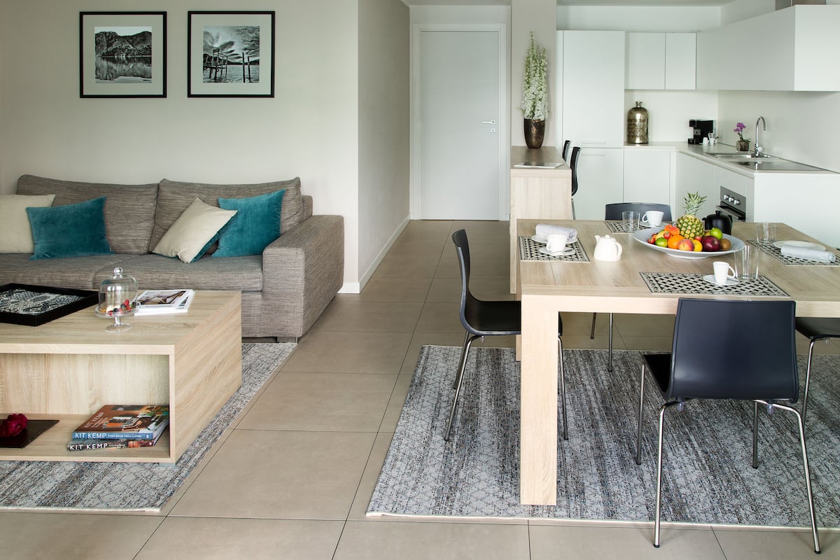 Een moderne woonkamer met een bank, salontafel en eethoek met stoelen en een tafel gedekt voor twee personen.
