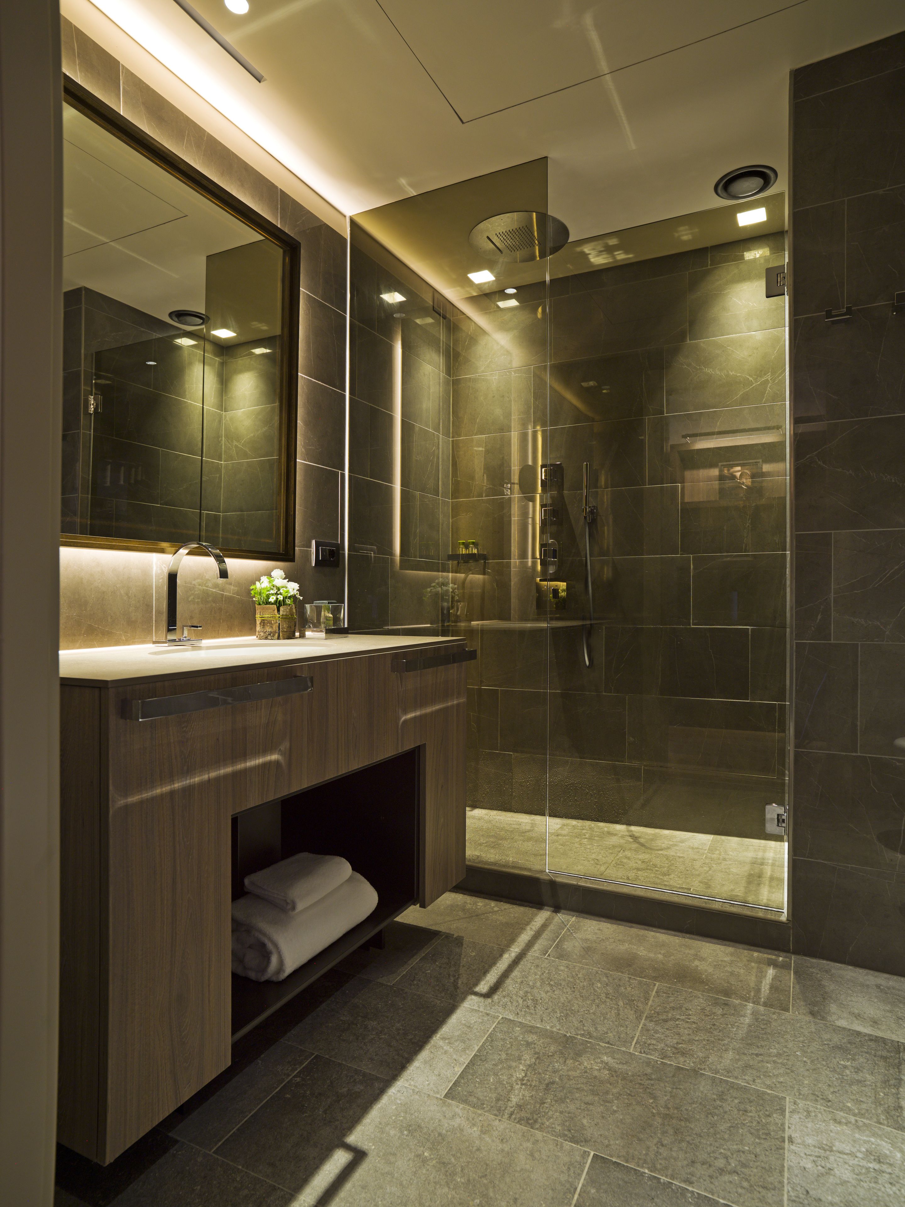 A modern bathroom with a glass-enclosed shower, a vanity with a mirror, and a towel rack.
