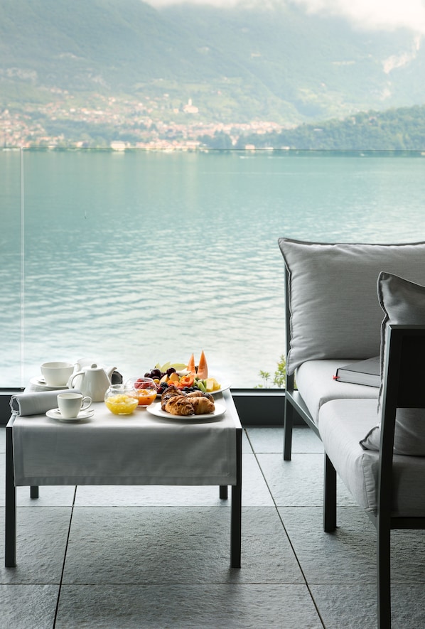 A dining table with breakfast items and a view of a lake. - Filario Hotel & Residences (Lezzeno)