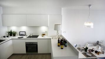 A modern kitchen with white cabinetry, a built-in oven, and a dining area with a table set for two.
