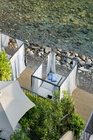 Eine Terrasse mit Sitzgelegenheiten, freier Blick auf die felsige Küste und ein kleiner Gartenbereich.