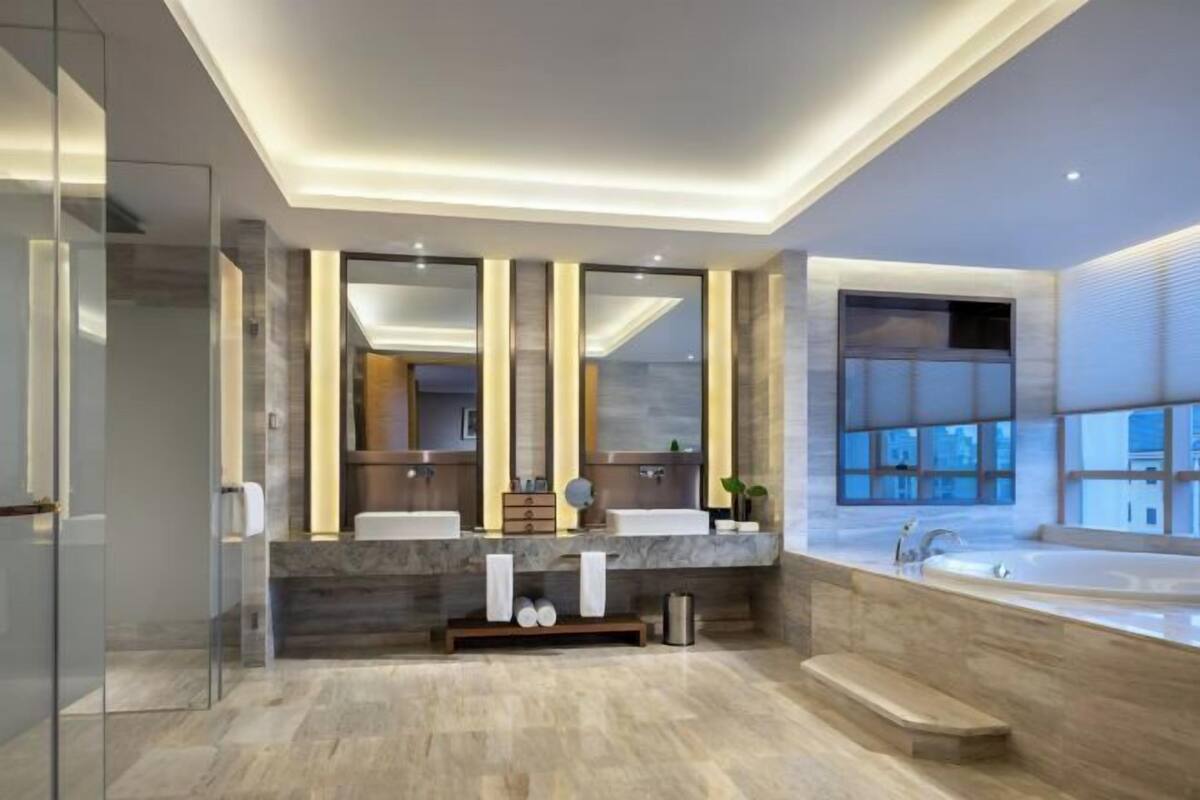 Une salle de bain moderne avec deux lavabos, un grand miroir et une baignoire.