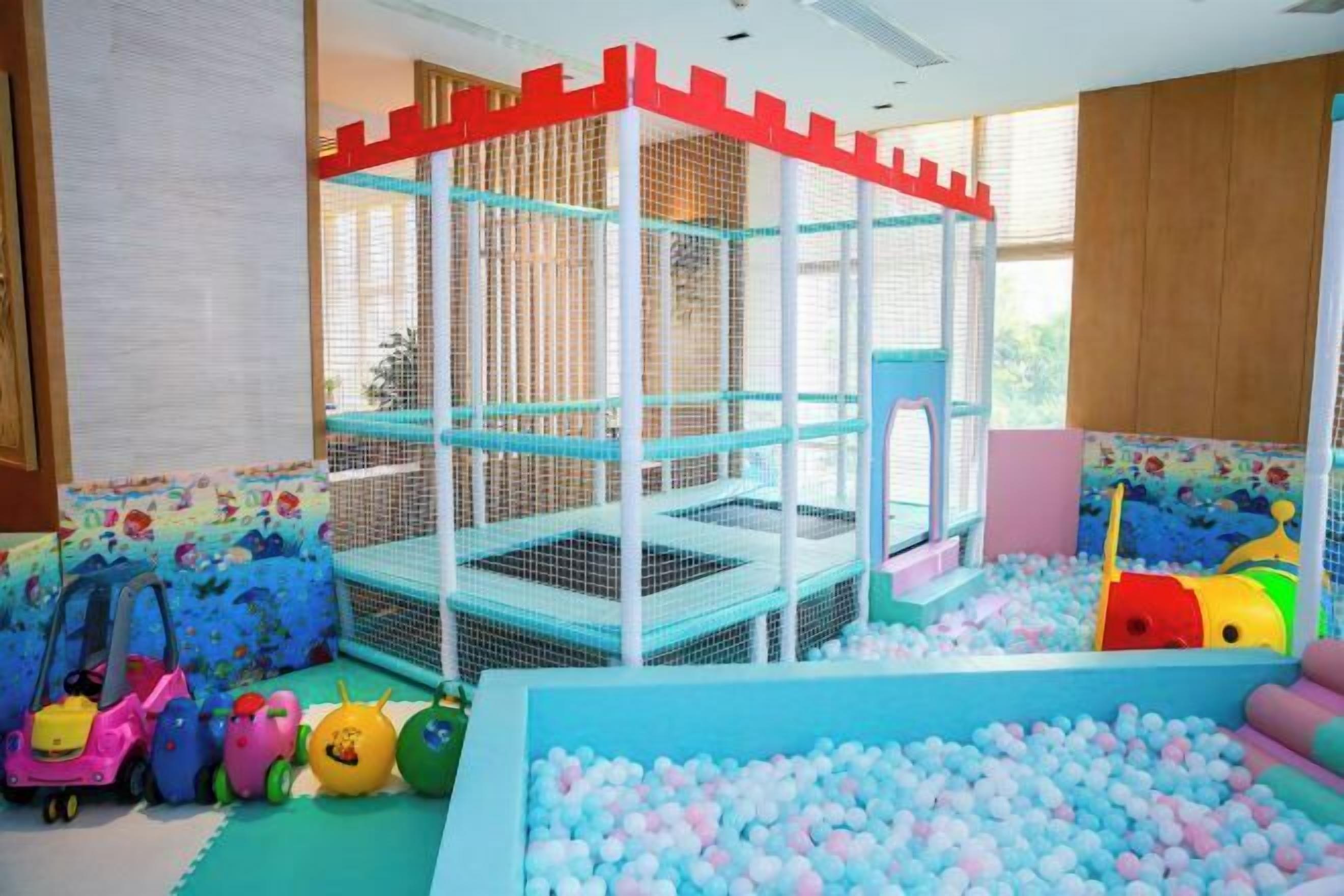 Zona de juegos infantiles con piscina de pelotas y estructura para escalar.