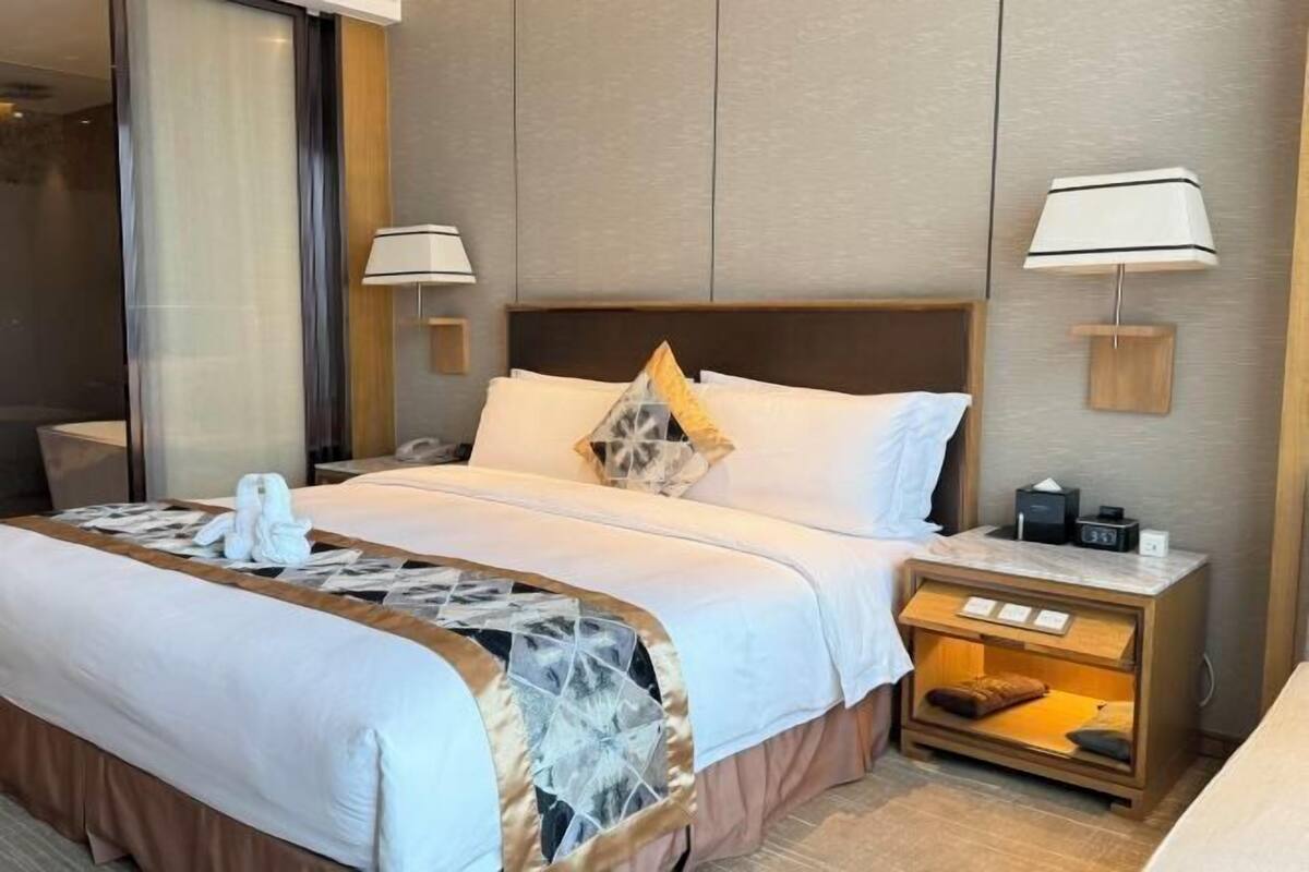 Une chambre d’hôtel avec un lit, des lampes de chevet, une table de nuit et un miroir.