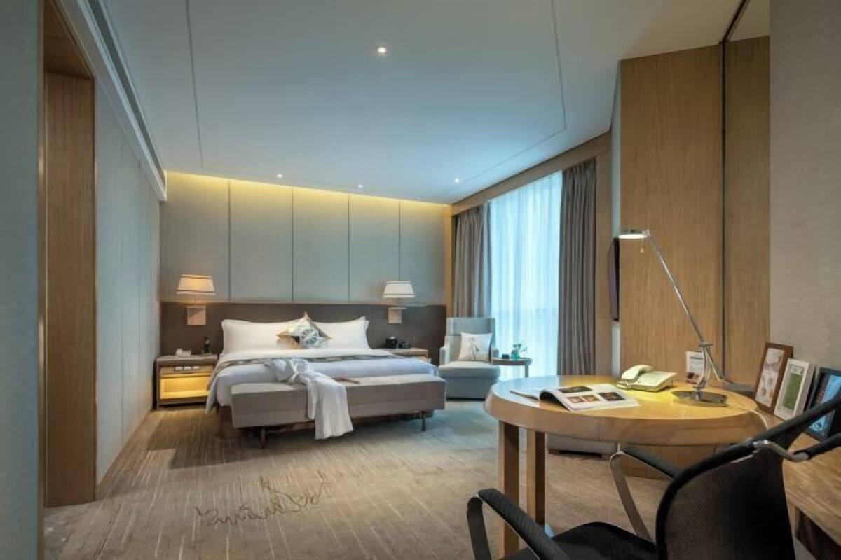 Une chambre d’hôtel moderne équipée d’un lit, de tables de chevet, d’un bureau et d’une chaise.
