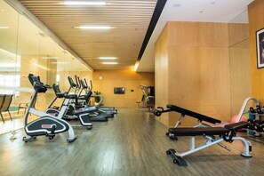 Een fitnessruimte met loopbanden, een bankdrukapparaat en gewichtmachines.