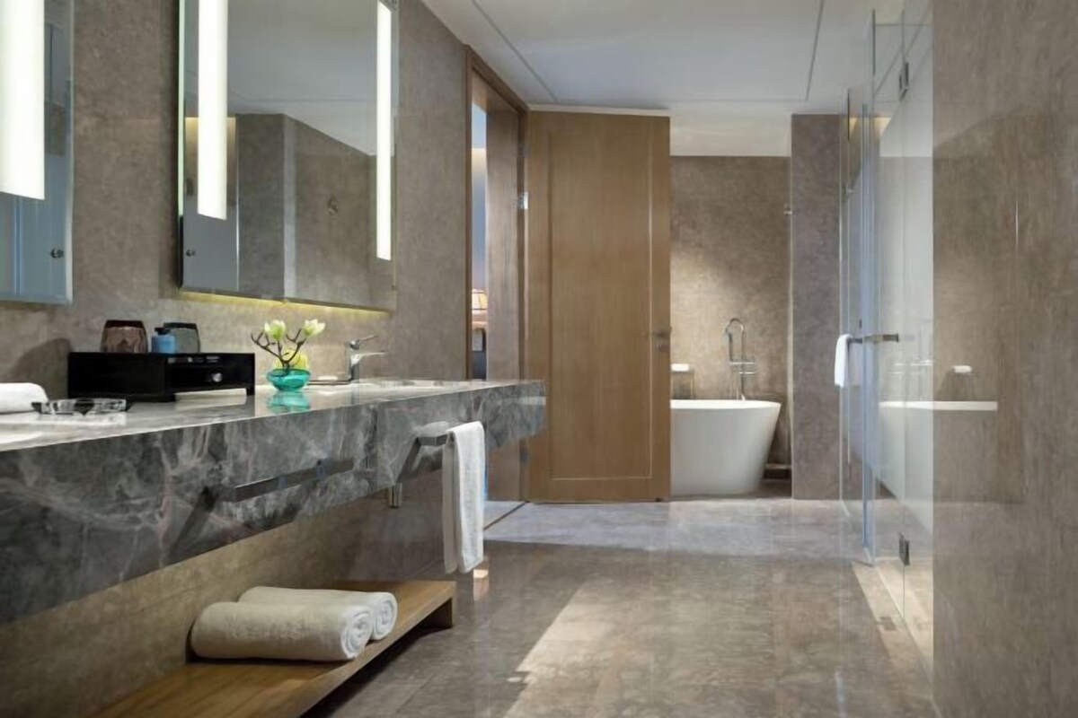 Un baño moderno con tocador de mármol, bañera independiente y cabina de ducha de vidrio.