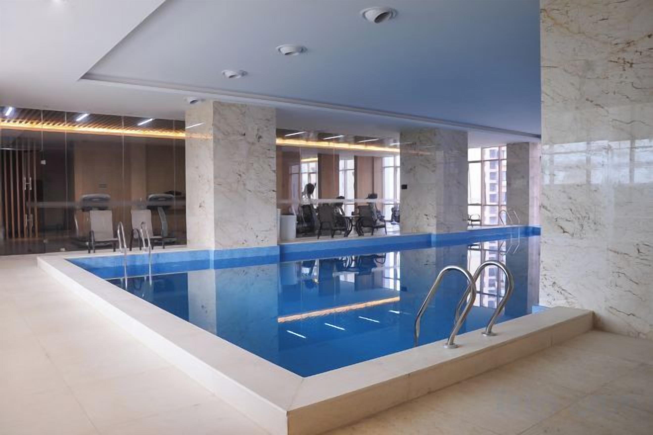 Una piscina interior con agua cristalina, rodeada de columnas de mármol y un diseño de interiores moderno.