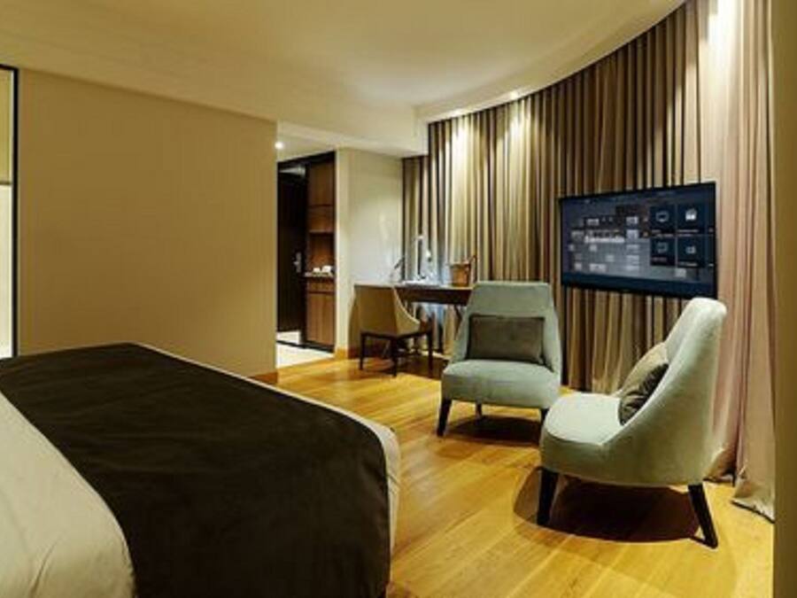 Een moderne hotelkamer met een groot bed, een bureau, een stoel en een televisie.