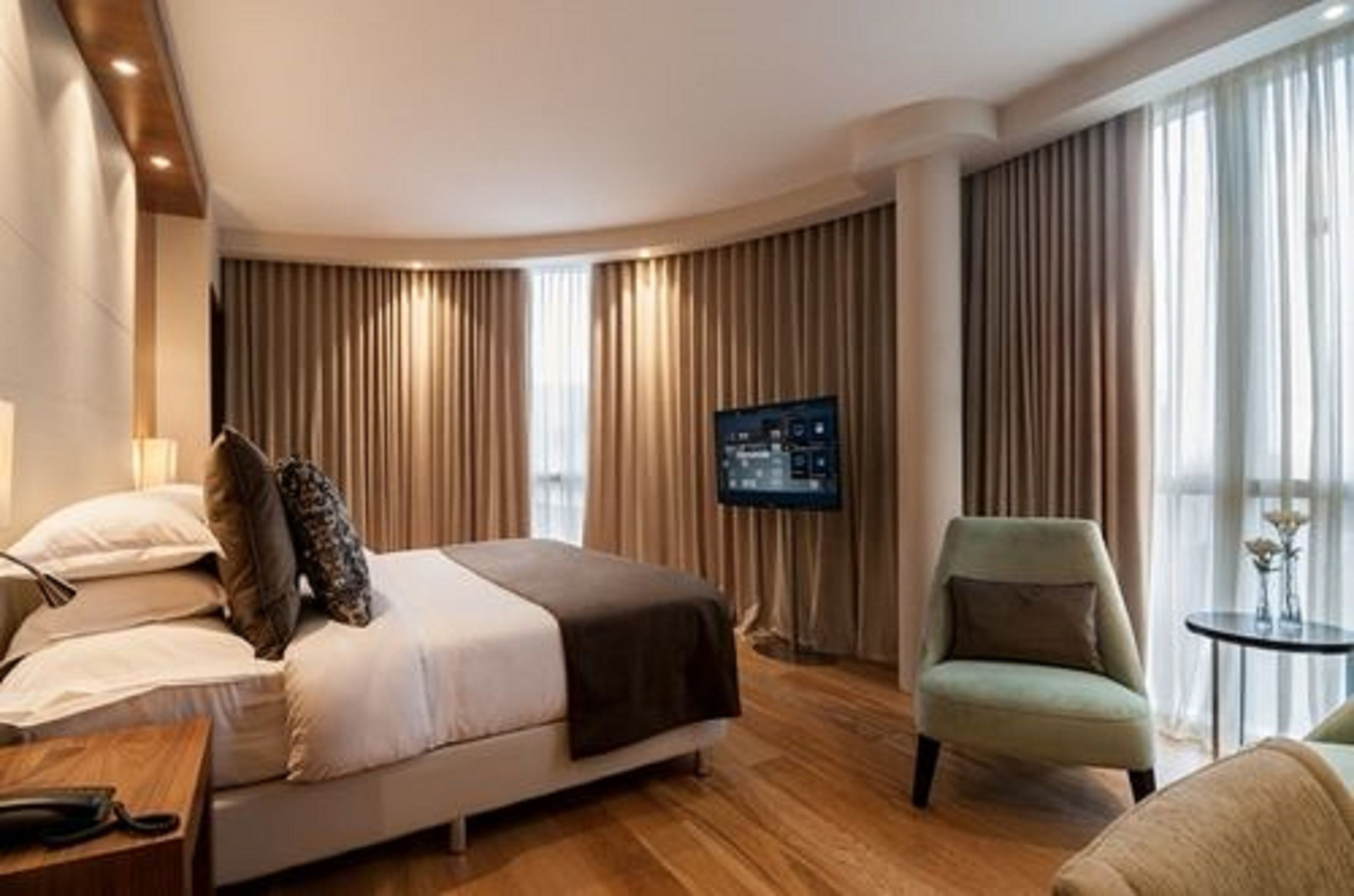 Habitació d'hotel amb un llit, una televisió, una cadira i una taula petita.