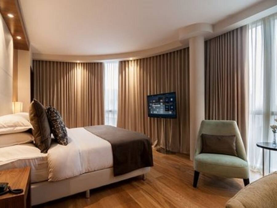 Habitació d'hotel amb un llit, una televisió, una cadira i una taula petita.