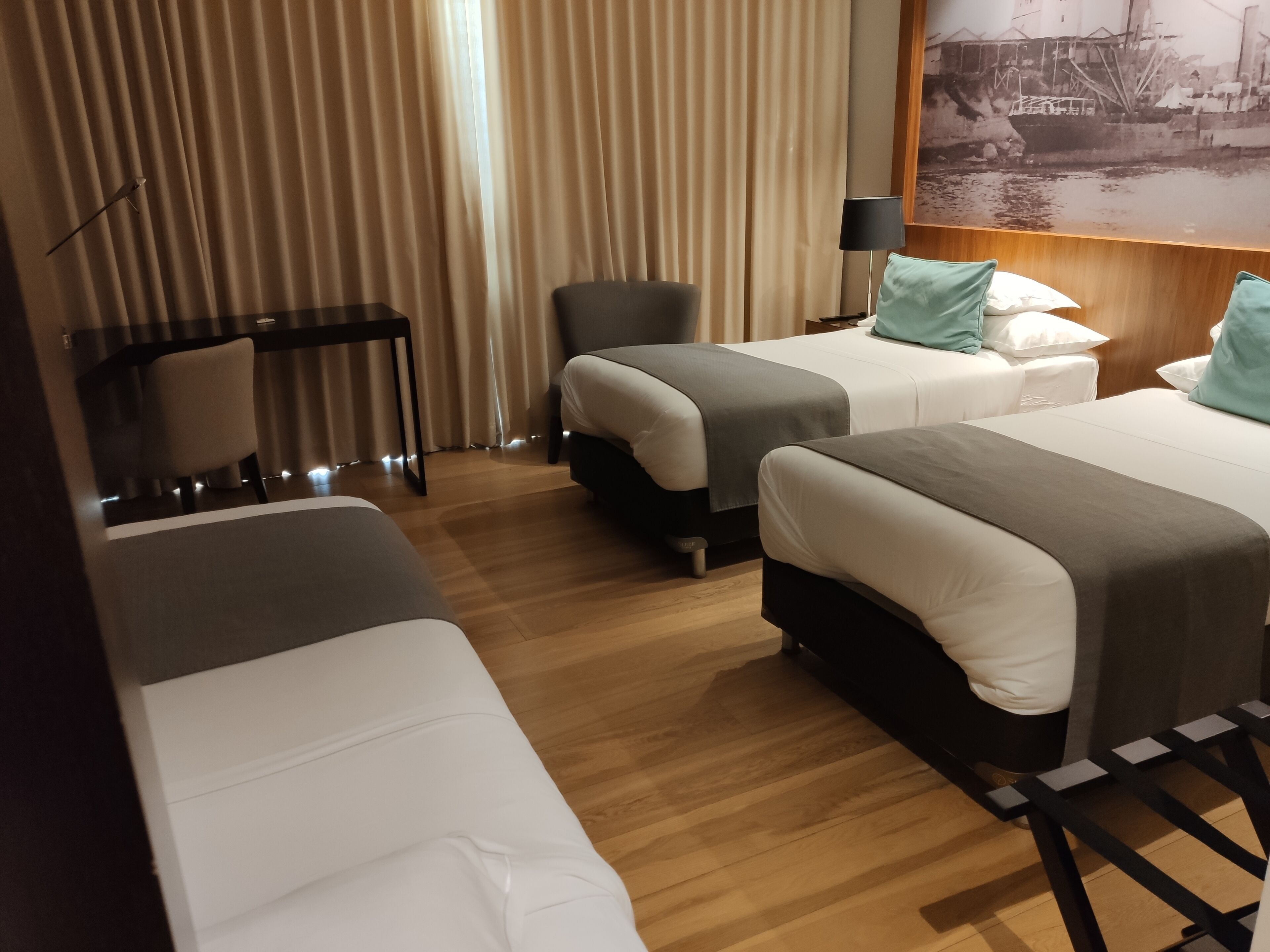Habitación de hotel con dos camas individuales, un escritorio y una silla.
