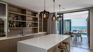 A modern kitchen with a central island, bar stools, and a view of the ocean. - Living Hotel Lions Eye (Cape Town)