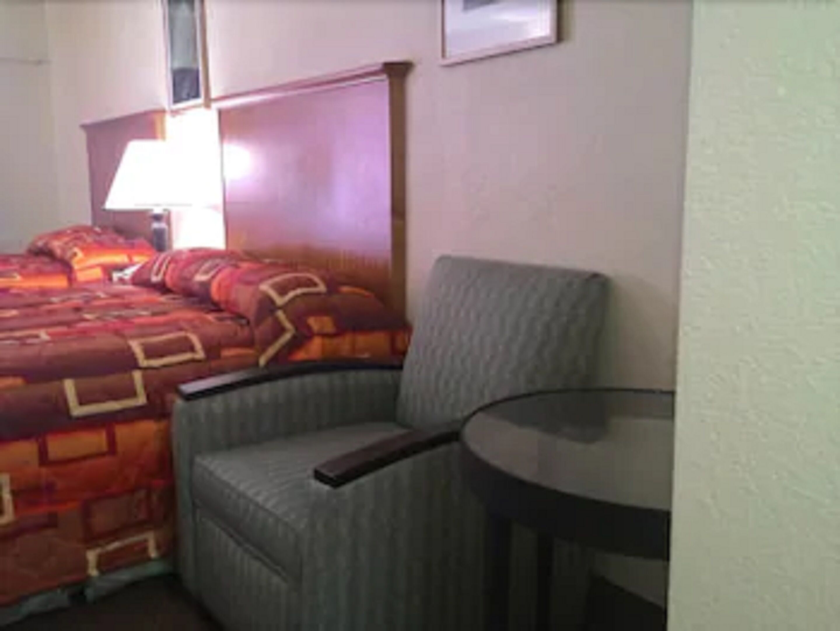 Una habitación de hotel con una cama, una silla y una mesita.