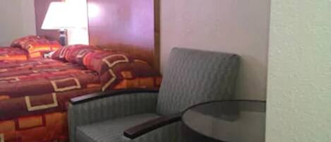 Una habitación de hotel con una cama, una silla y una mesita.