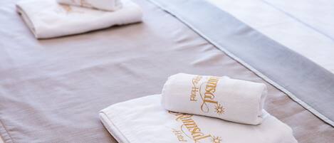 Neatly folded white towels with gold lettering on a bed.