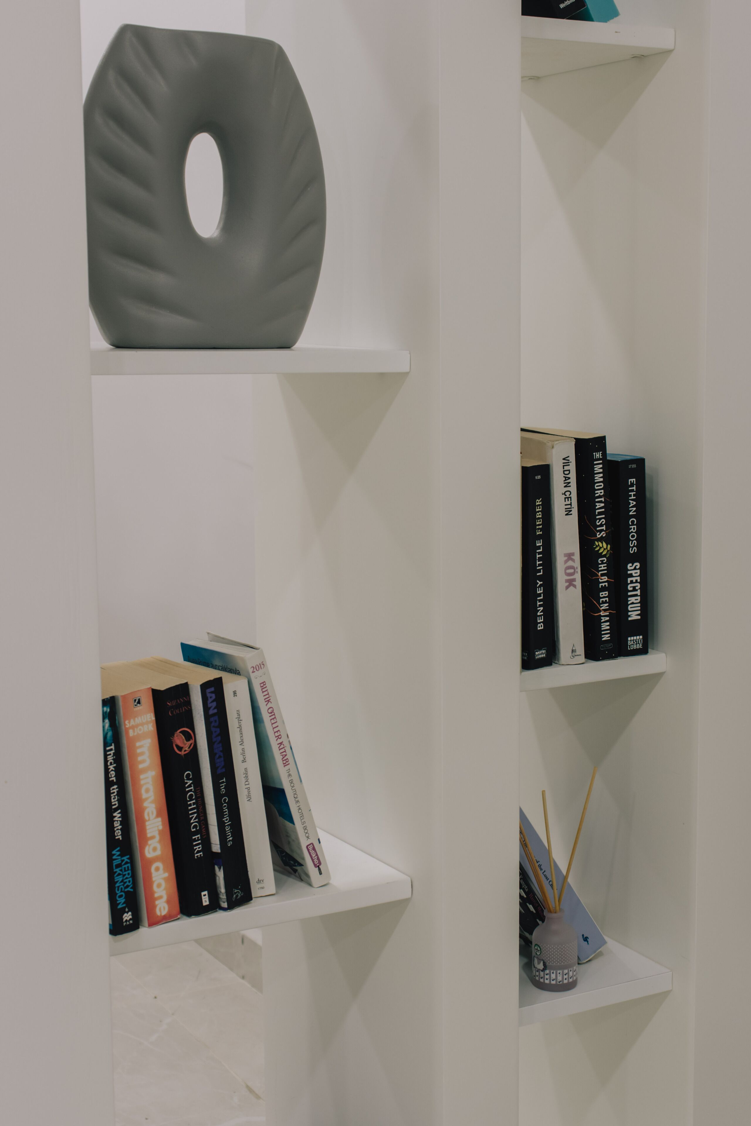Una estantería con libros y un objeto decorativo.