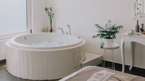 Un baño moderno con una bañera independiente, un tocador con espejo y una planta en maceta.