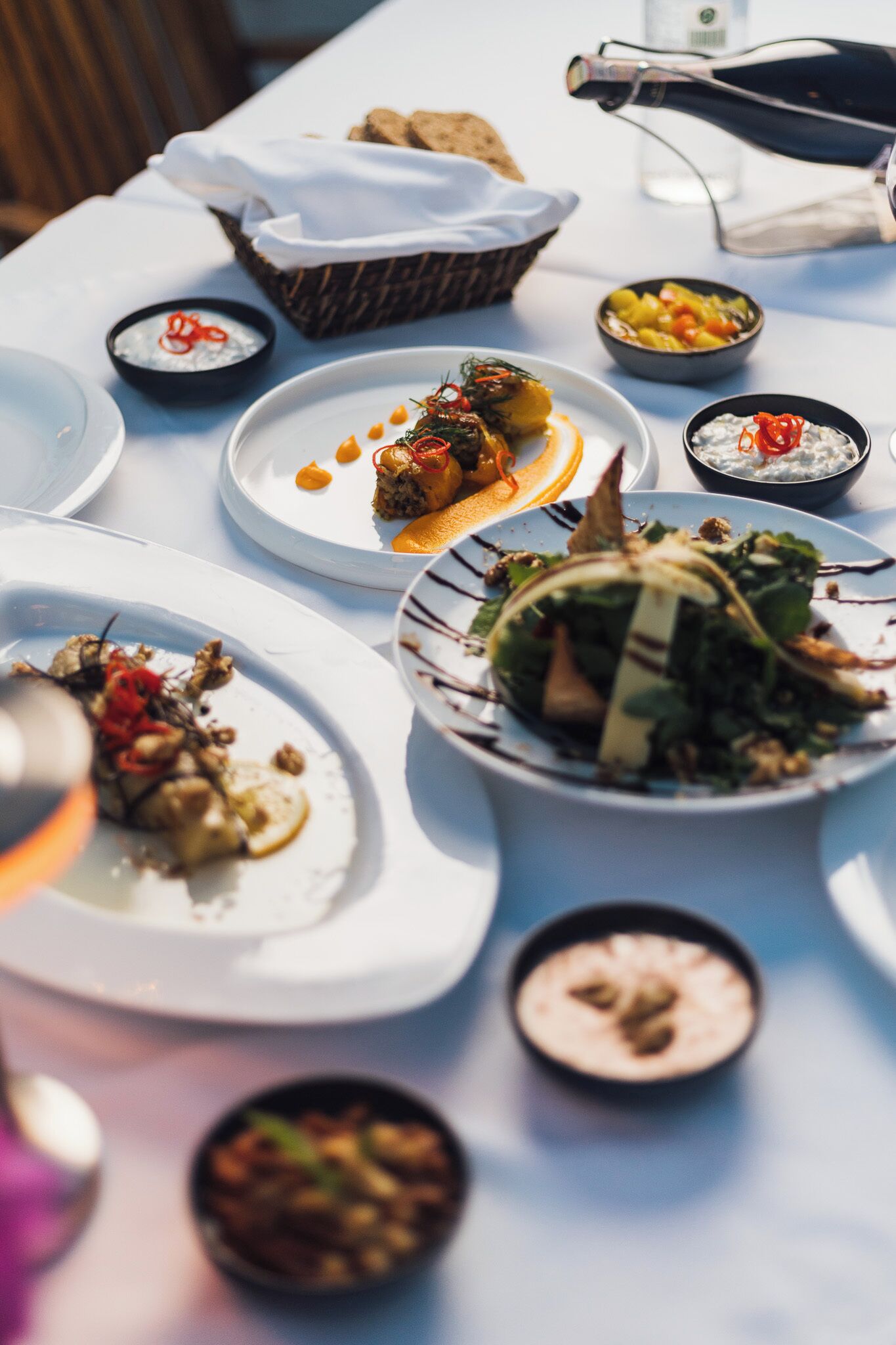 A table set with various dishes, including a salad, a bowl of soup, and a plate with a dessert.