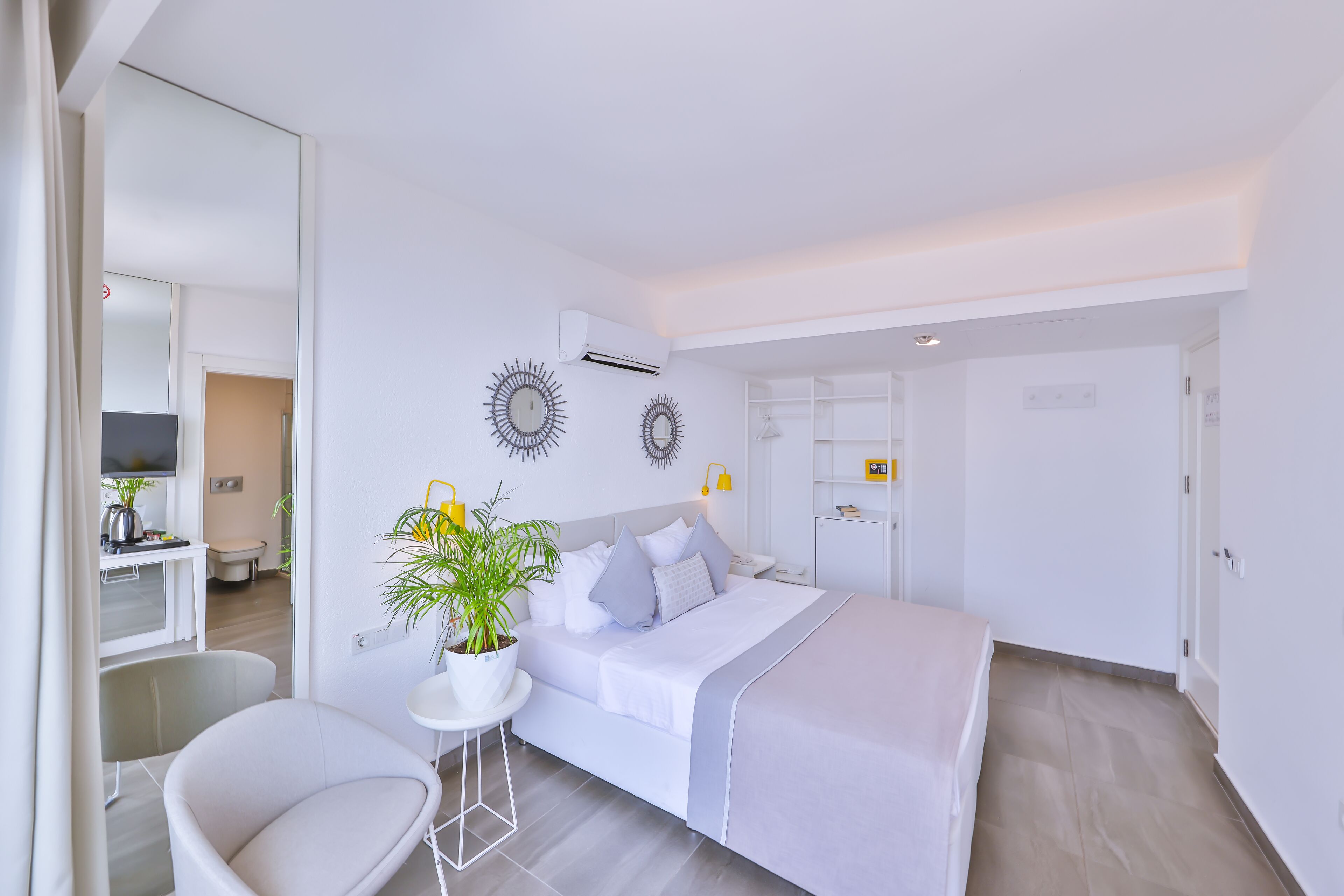 Een moderne slaapkamer met een bed, nachtkastje en een potplant.