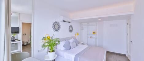 A modern bedroom with a bed, bedside table, and a potted plant.