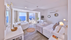 Habitación de hotel moderna con una bañera grande, una cama, un escritorio y vistas al mar.