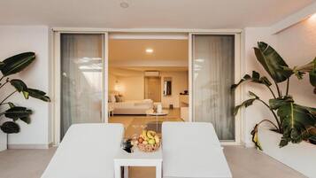 A modern living room with a sofa, a coffee table with fruit, and a view into another room.