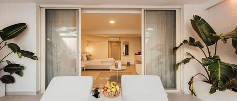 A modern living room with a sofa, a coffee table with fruit, and a view into another room.