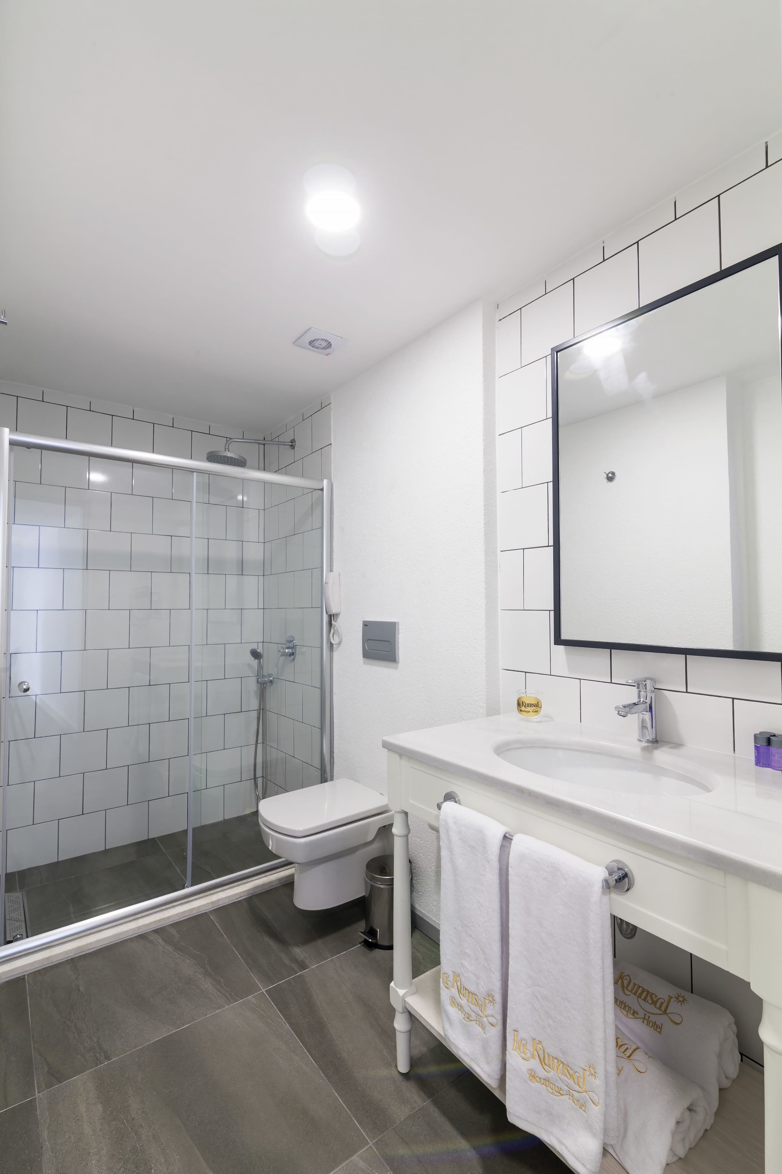 A modern bathroom with a glass-enclosed shower, a white sink, and a large mirror.