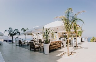 Terraza en la azotea con mobiliario exterior, sombrillas y plantas en macetas.