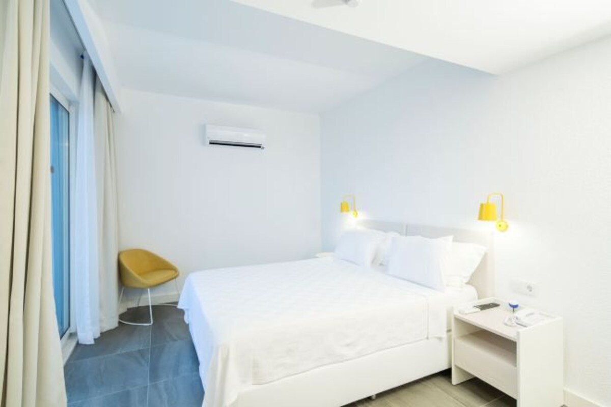 A modern hotel room with a bed, bedside table, and a chair.