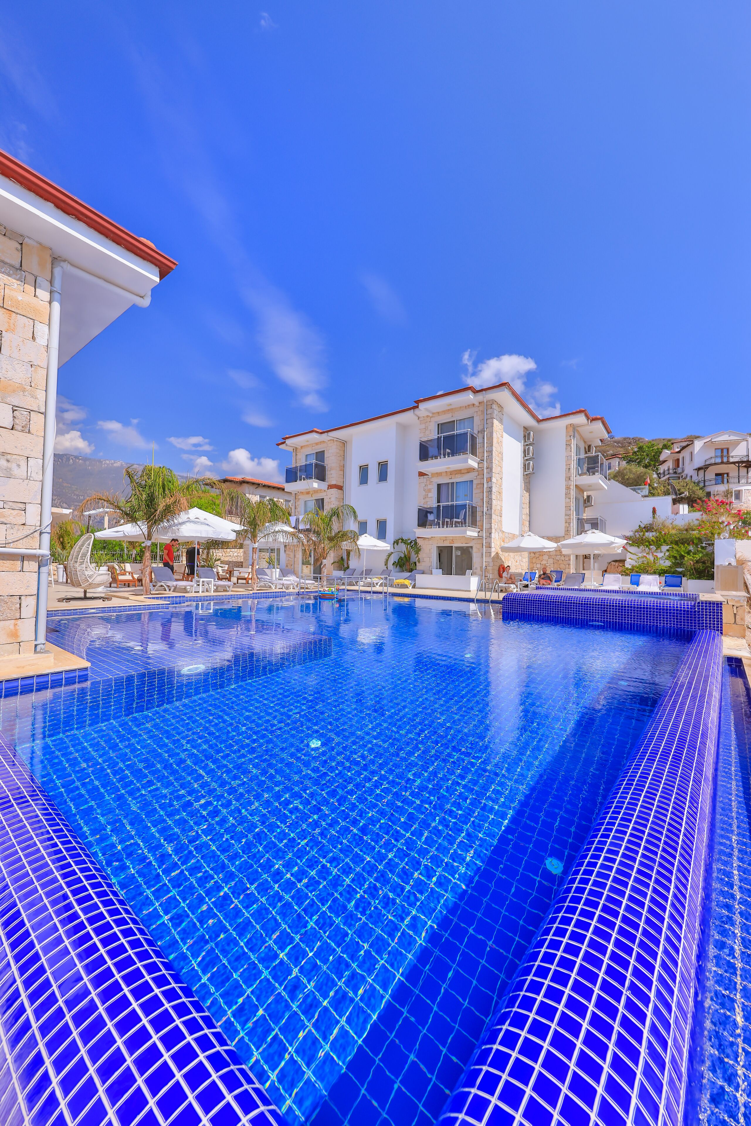 Una piscina al aire libre, sombrillas, sillones reclinables de piscina