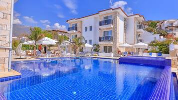 Alberca al aire libre, sombrillas en la alberca y camastros