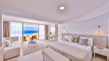 Un dormitorio moderno de hotel con una cama grande, un escritorio y vistas al océano.