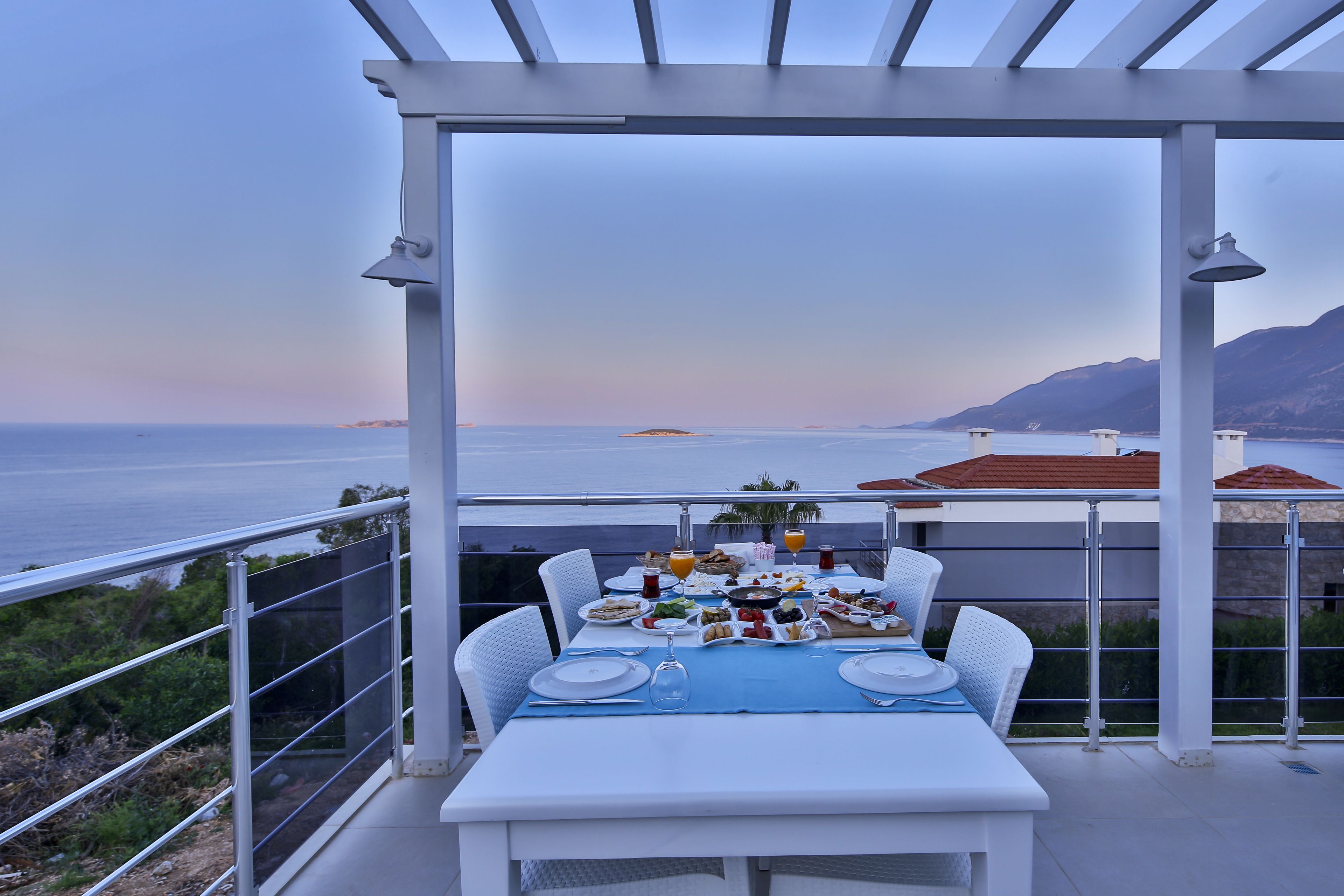 A terrace with a table set for a meal, overlooking the sea.