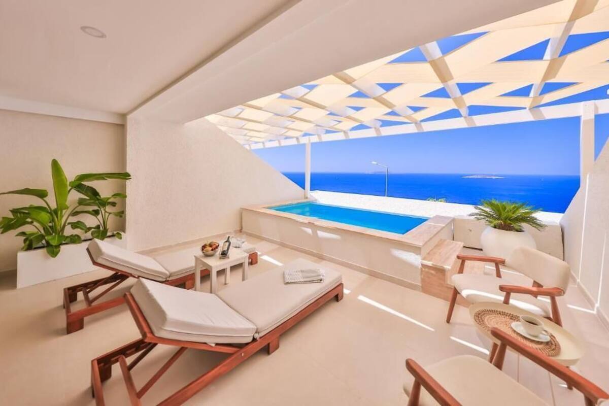 A modern balcony with a pool, lounge chairs, and a view of the sea.