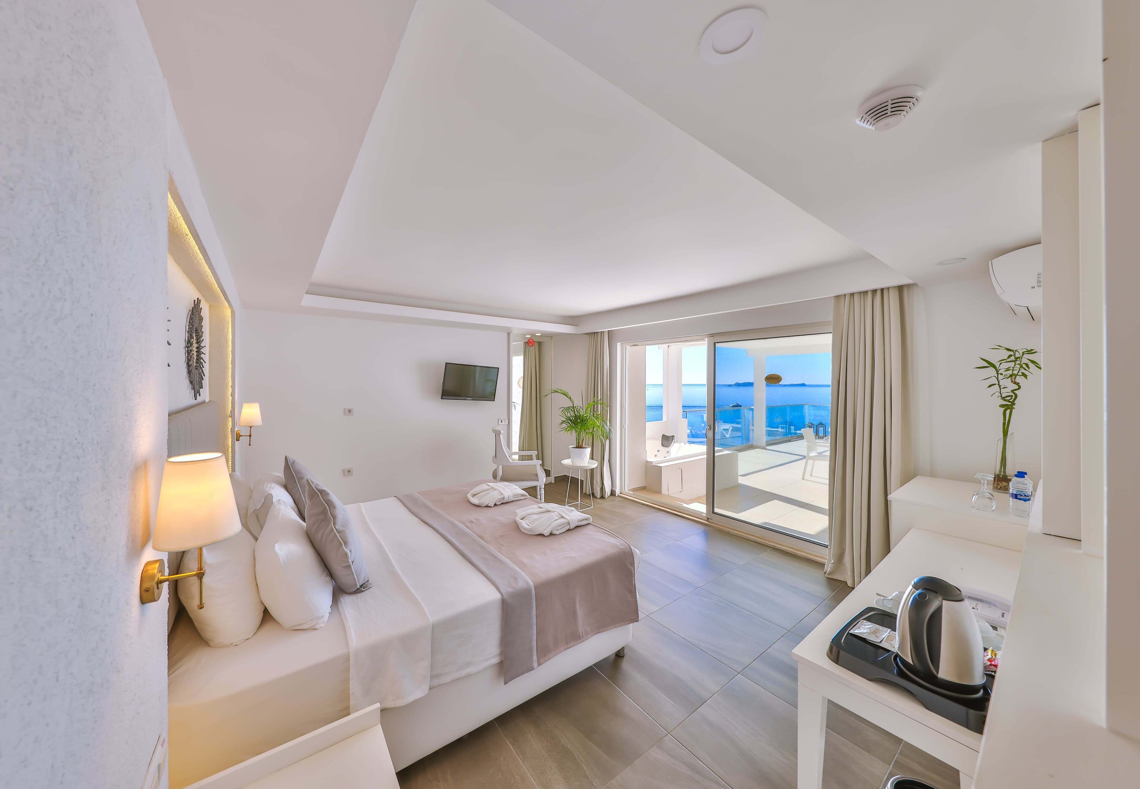 Una habitación de hotel moderna con una cama, mesita de noche y vistas al mar.