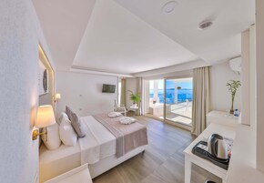 Una habitación de hotel moderna con una cama, mesita de noche y vistas al mar.