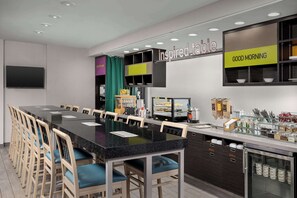 Eine moderne Frühstücksbar mit einer langen Theke, verschiedenen Sitzgelegenheiten und einer Auswahl an Frühstücksangeboten.