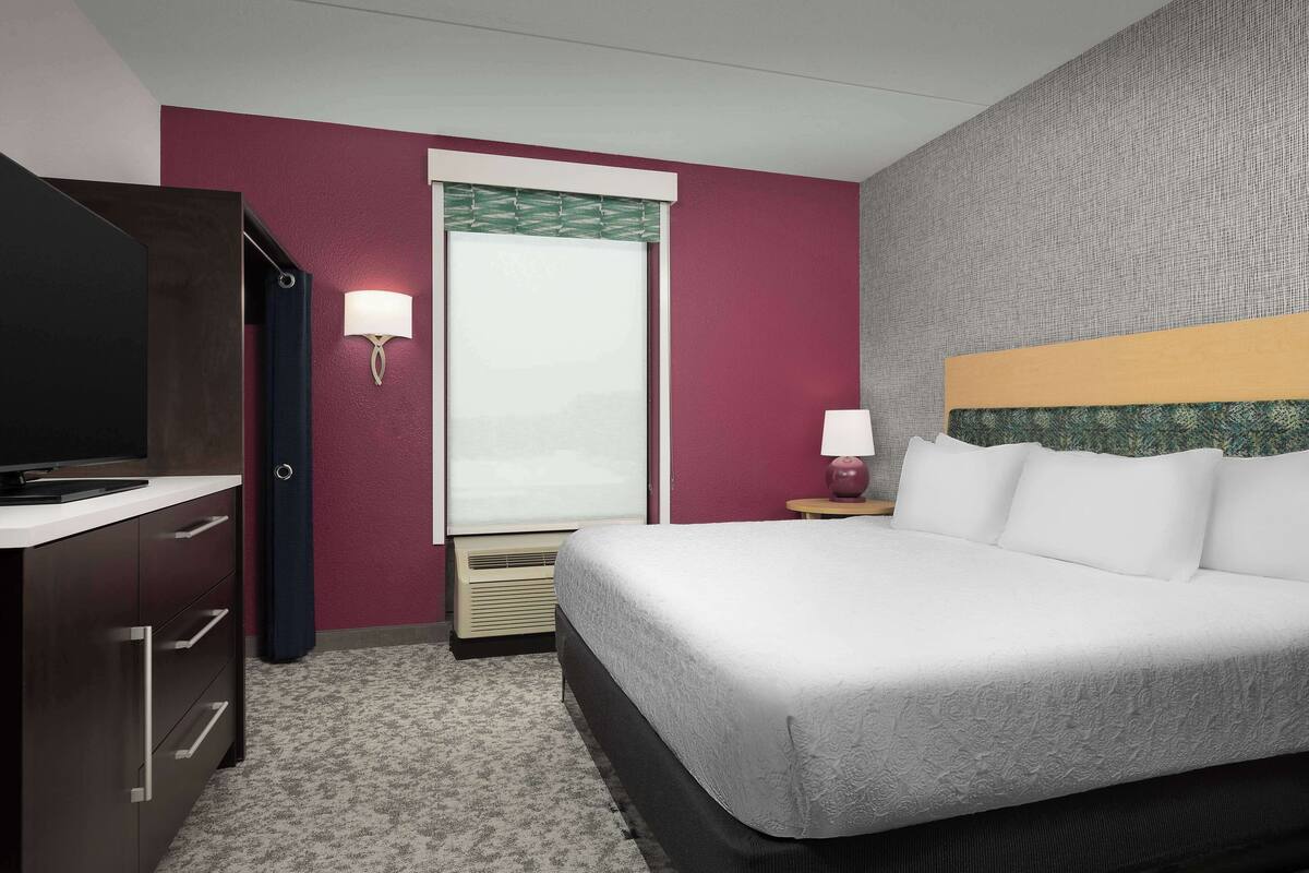 Une chambre d’hôtel avec un lit, une télévision, un bureau et une fenêtre donnant sur un paysage agréable.