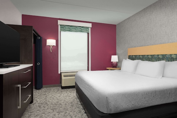 Habitación de hotel con cama, televisor, escritorio y ventana con vistas.