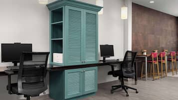 Un espacio de oficina moderno con muebles de color verde azulado, sillas de oficina negras y una mesa larga con sillas rojas.
