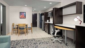 A modern kitchen with a dining area, a microwave, and a desk with a lamp. - Home2 Suites by Hilton Knoxville West (Knoxville)