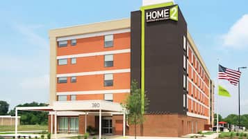 HOME 2 hotel features a striking facade with a flat roof and large windows, set amidst a beautifully landscaped garden.