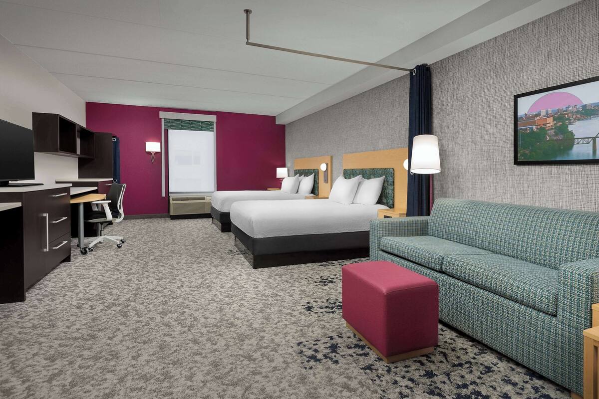 Une chambre d’hôtel comprenant un lit, un bureau, une chaise, un canapé et un téléviseur.